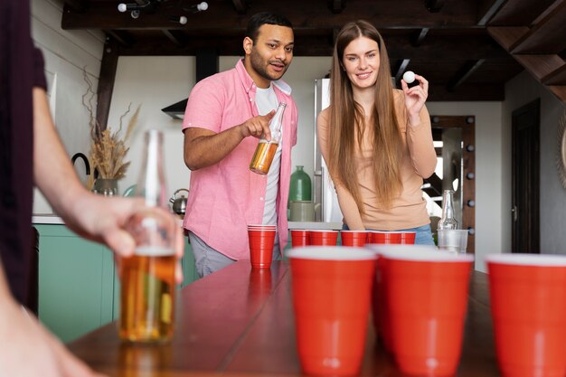 Amigos jugando Beer pong juntos en una fiesta