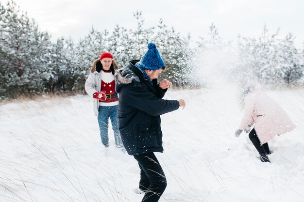 Amigos jugando bolas de nieve en el bosque de invierno