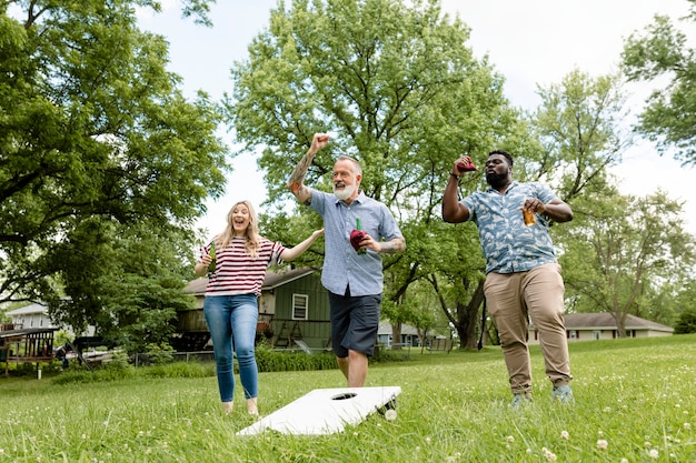 Foto gratuita amigos jugando cornhole en una fiesta de verano en el parque