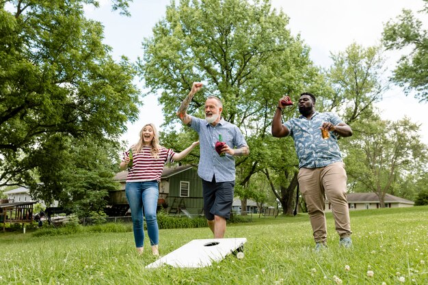 Amigos jugando cornhole en una fiesta de verano en el parque