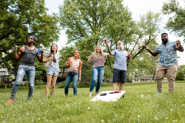 Amigos jugando cornhole en una fiesta de verano en el parque