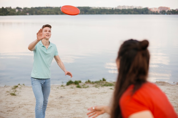 Foto gratuita amigos jugando con frisbee en la playa
