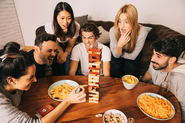 Amigos jugando juego de mesa con patatas fritas