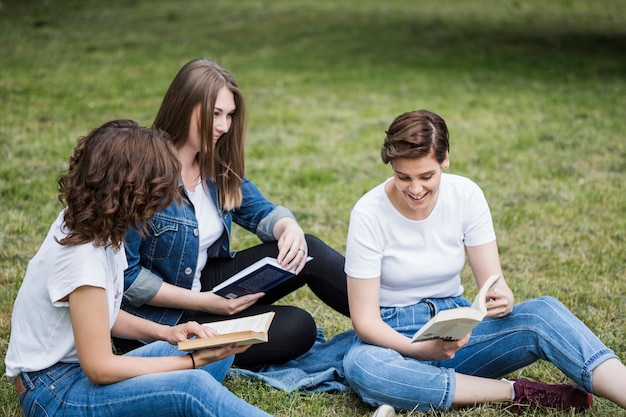 Amigos leyendo juntos sobre hierba