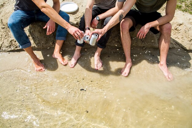 Amigos masculinos descalzos aplaudiendo con cerveza