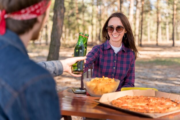 Amigos masculinos y femeninos brindis con cerveza sobre pizza