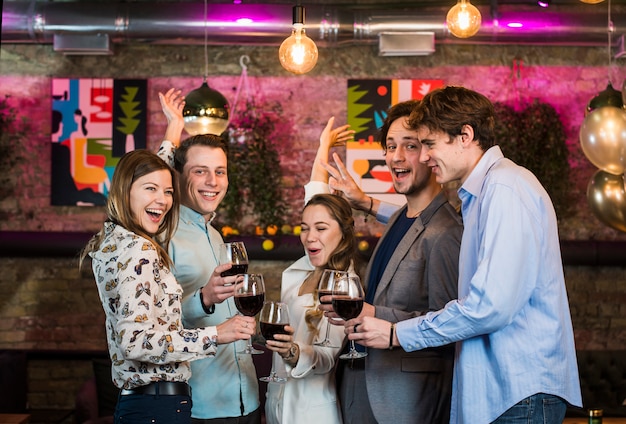 Amigos masculinos y femeninos disfrutando de bebidas mientras bailan en el bar