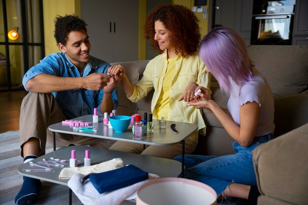 Amigos masculinos y femeninos haciéndose la manicura juntos