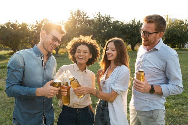 Amigos masculinos y femeninos pasar tiempo juntos al aire libre y tomar cerveza