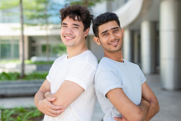 Amigos masculinos multiétnicos jovenes que se unen y que sonríen