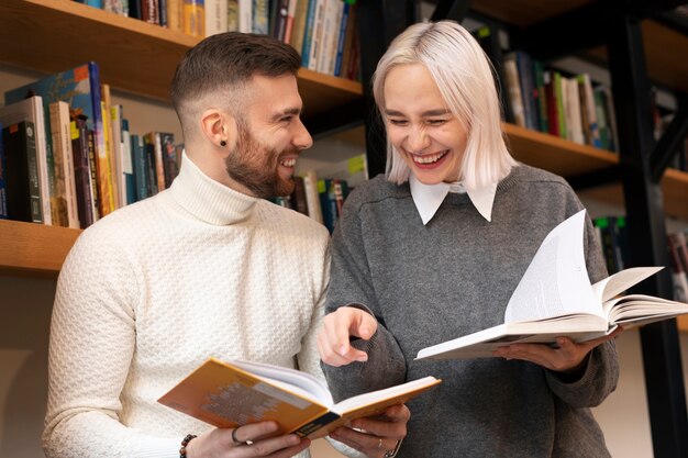 Amigos mirando libros en una biblioteca y riendo