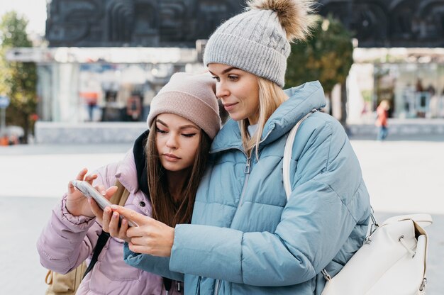 Amigos mirando un teléfono al aire libre en invierno