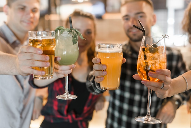 Amigos mostrando vasos de bebidas cócteles