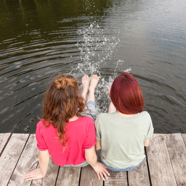 Foto gratuita amigos en el muelle y salpicando agua con los pies +