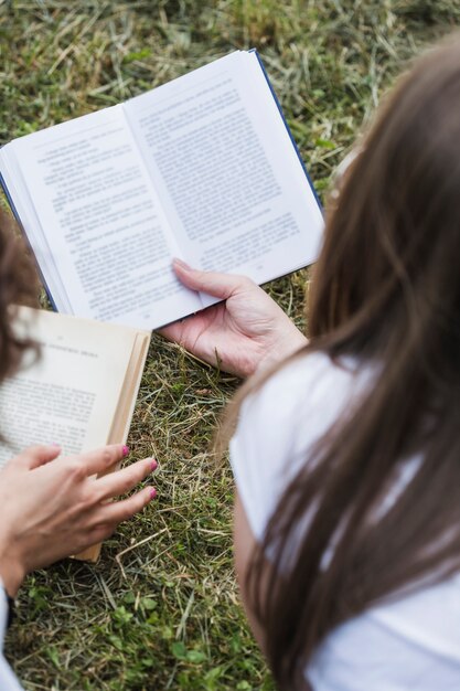 Amigos de mujeres de cultivos leyendo libros sobre hierba