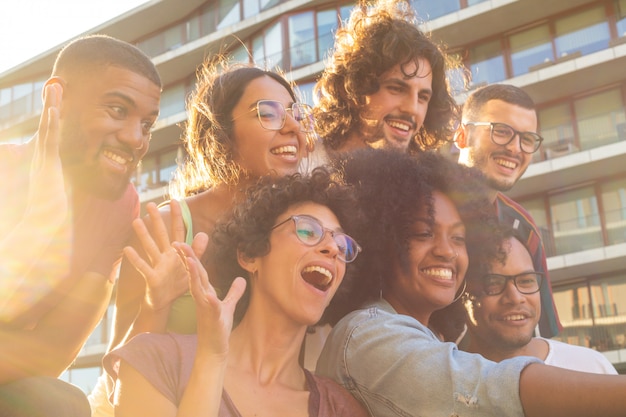 Amigos multiétnicos alegres que toman selfie grupal divertido