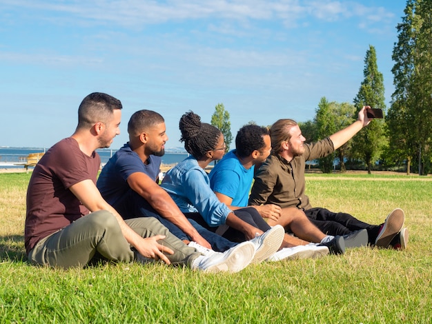 Amigos multiétnicos tomando selfie en el parque