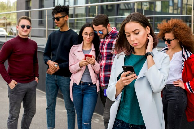 Amigos multiétnicos usando teléfono móvil al aire libre