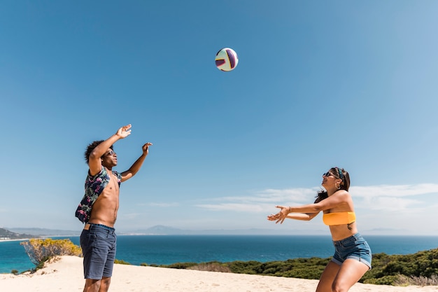 Amigos multirraciales jugando voleibol de playa.