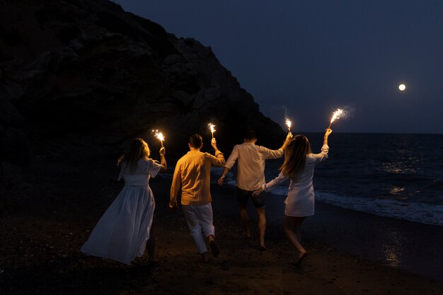 Amigos de noche en la playa con antorchas