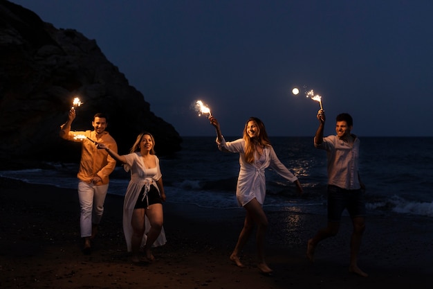 Amigos de noche en la playa con antorchas