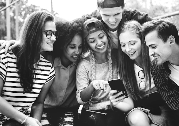 Amigos en el parque mirando usando teléfonos inteligentes concepto de cultura milenaria y juvenil