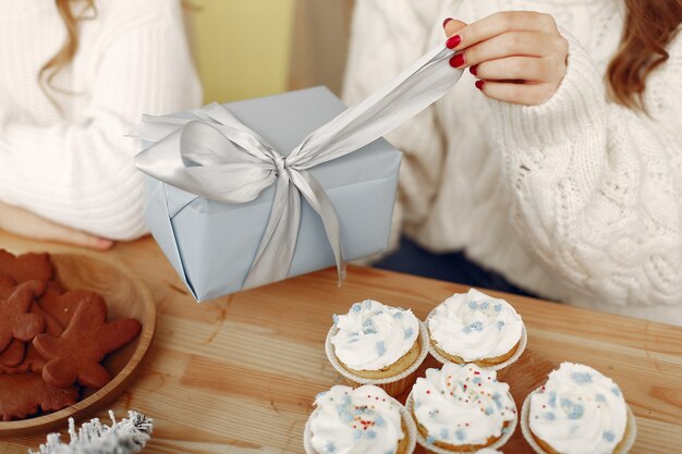 Los amigos pasaban tiempo en casa. Dos chicas con regalo de Navidad. Mujer con sombrero de santa.