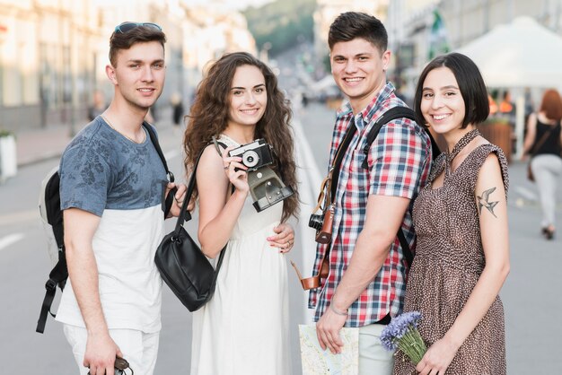 Amigos de pie en la calle con cámara y mapa