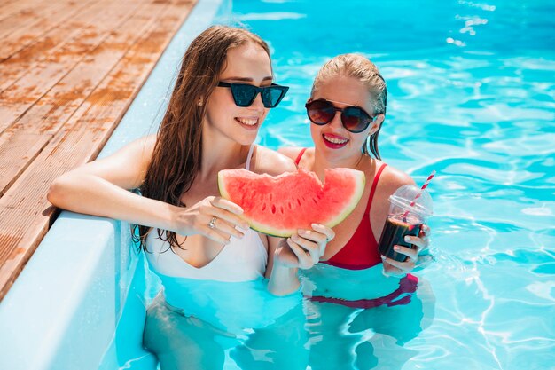 Amigos en la piscina sosteniendo una sandía