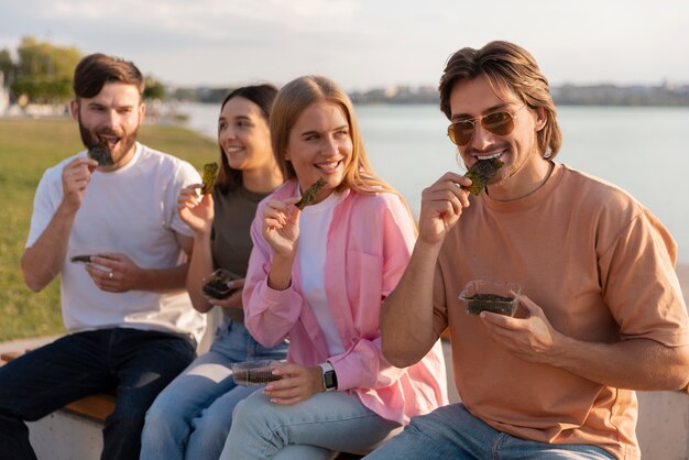 Amigos de plano medio comiendo bocadillos de algas