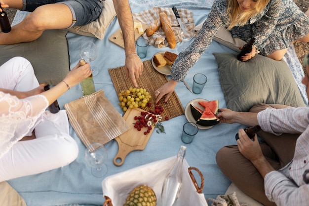 Amigos en la playa con comida y bebida.