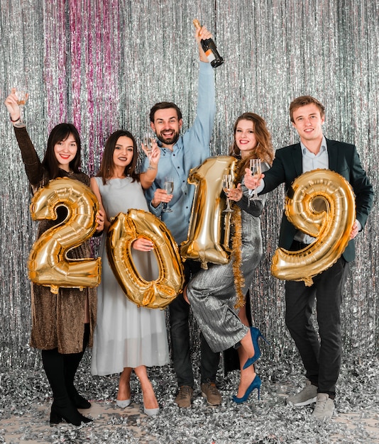 Amigos posando con globos dorados fiesta año nuevo