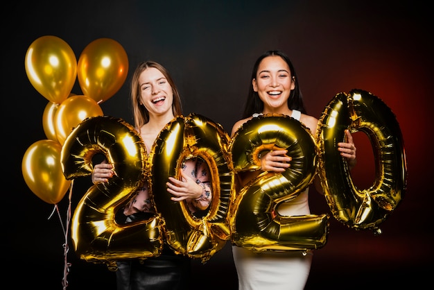 Amigos posando con globos dorados en fiesta de año nuevo