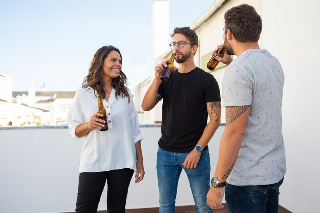 Amigos positivos relajados disfrutando de la noche y bebiendo cerveza