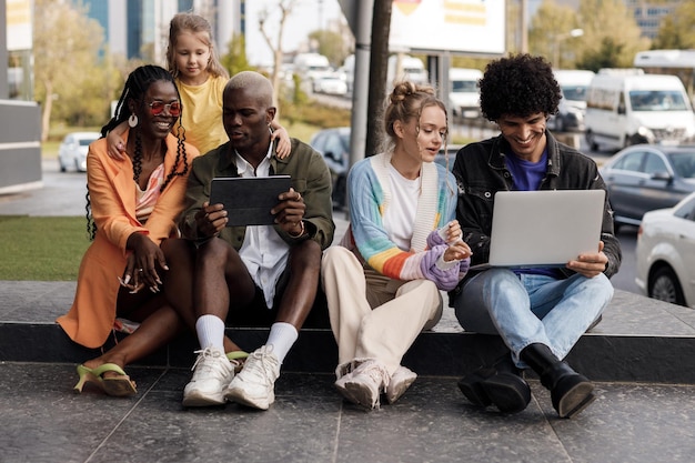 Amigos positivos trabajando con laptop al aire libre