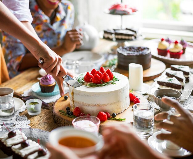 Amigos que se reúnen en la fiesta del té Comer tortas Disfrutar la felicidad