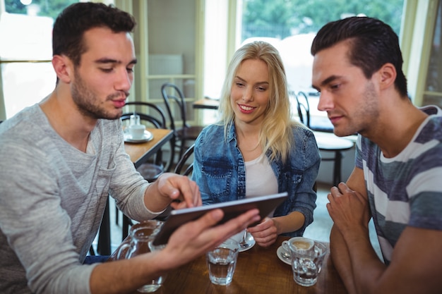 Amigos que usa la tableta digital mientras se come la taza de café