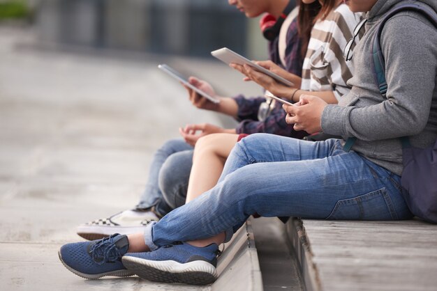 Amigos que usan dispositivos al aire libre