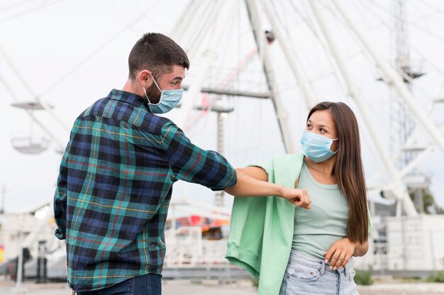 Amigos que usan el saludo del codo mientras usan máscaras médicas