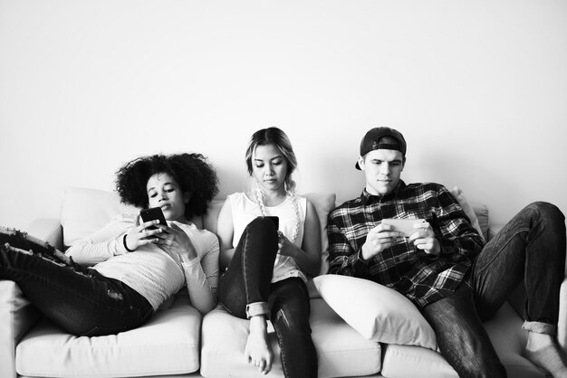 Amigos que usan teléfonos móviles en el sofá