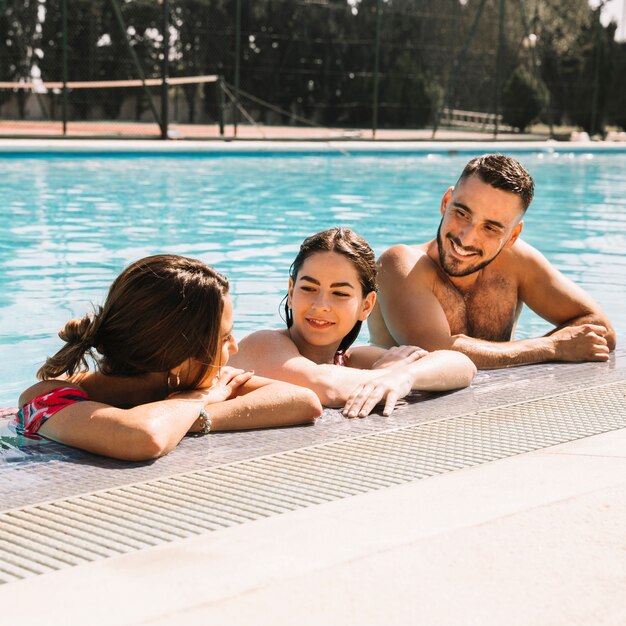 Amigos relajando al lado de piscina