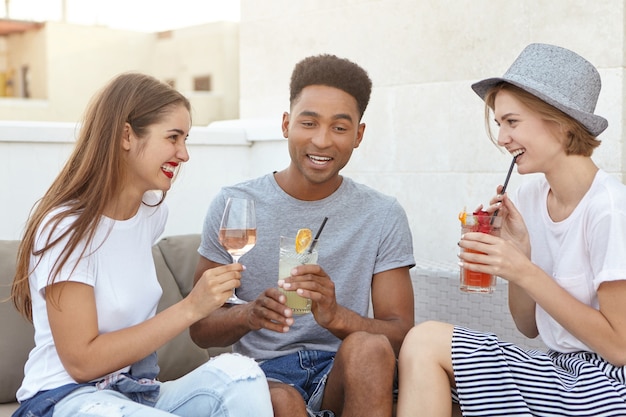 amigos reunidos bebiendo vino blanco y cócteles frescos mientras discuten algo
