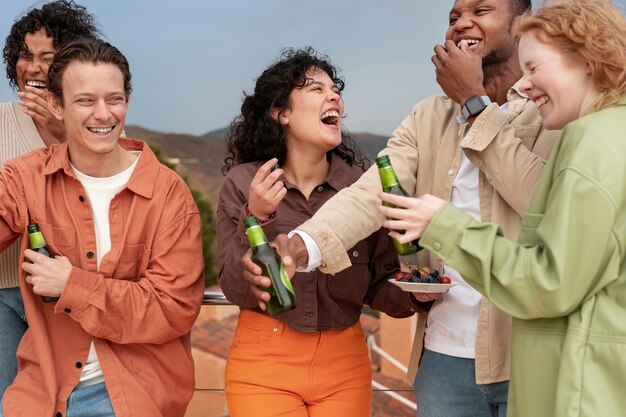 Amigos riendo y bebiendo cerveza durante la fiesta al aire libre