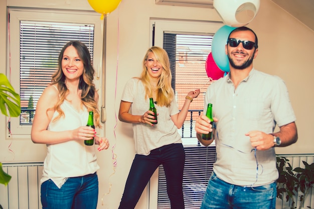 Amigos riéndose en la fiesta con botellas de cerveza