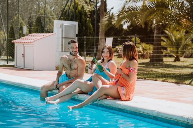 Amigos sentado por la piscina