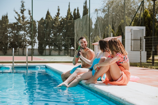 Amigos sentado por la piscina