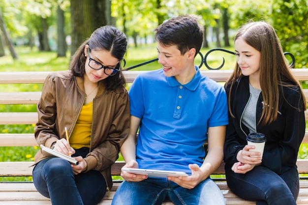 Amigos sentados en el banco y estudiando