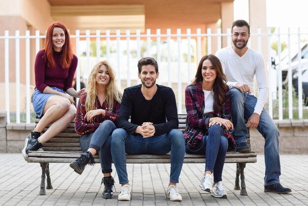 Amigos sentados en un banco de madera en la calle