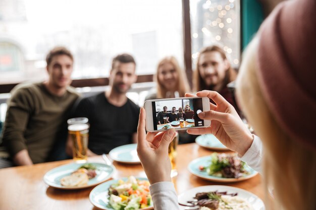 Amigos sentados en la cafetería y beber alcohol y hacer photo