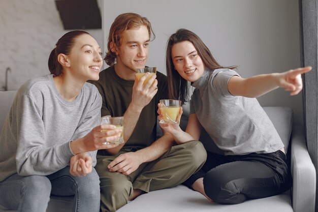 Amigos sentados en una cama en una habitación con jugo de naranja